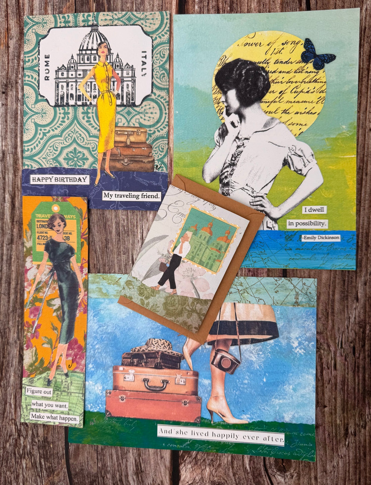 Inn Retrospect's original artwork lay across a wooden table. The artwork includes bookmarks, greeting cards, and flat collages for framing.