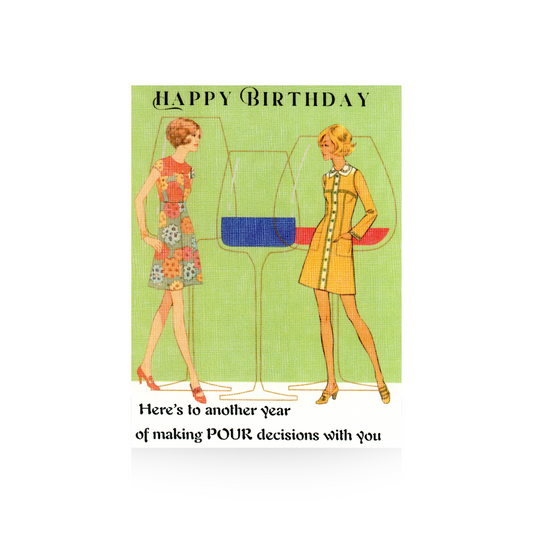 This birthday card features an oversized outline illustration of three wine glasses.  Two vintage women in short dresses, one flowered and one yellow, stand in front of the wine glass outline looking at each other.  The background is green and the base is white.  The greeting "Happy Birthday - Here's to another year of making POUR decisions with you" is printed on the top and bottom of the card