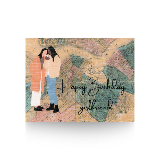 This birthday card features two modern illustrated women standing on top of a vintage map of Brooklyn New York City.  One woman is dark-skinned and is wearing jeans and a tan coat.  The other woman has long brown hair and is wearing light pants and tan long coat.  The greeting "Happy Birthday girlfriend" is written in cursive on the bottom right hand side of the card 