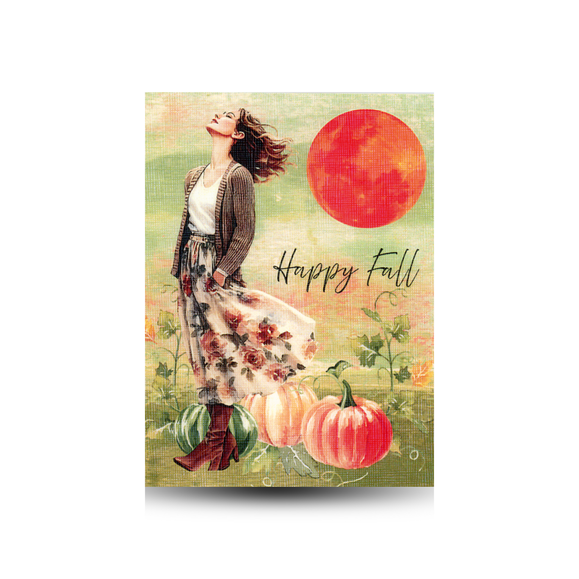 This Happy Fall greeting card features a modern woman with a flowered print skirt, brown boots, and a brown cardigan with a white shirt.  She is looking up at the sky with her hands in her pockets.  The background is a muted sky of orange and green with a green ground.  There is a large orange sun in the right hand upper corner and there are pumpkins and vines on the ground beside the girl.  Happy Fall is written in script font to the right of the girl
