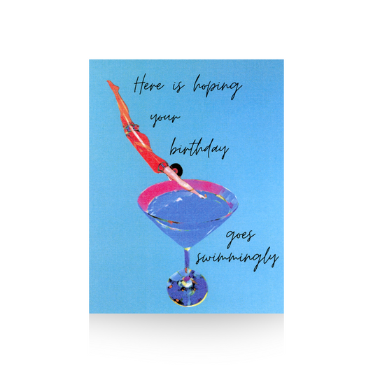 This birthday card features a blue background and a blue martini glass, into which an art deco lady in a vintage bathing suit is diving.  The message "Her is hoping your birthday goes swimmingly" is written in cursive font at the top and right hand side of the card