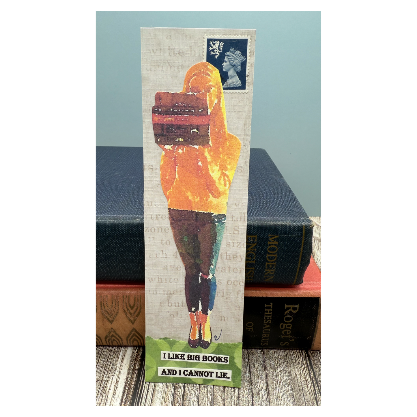 This paper collaged bookmark features a modern young woman in jeans holding a stack of books, with a blue background and green grass beneath her.  There is a UK postage stamp in right corner of Queen Elizabeth.  The quote is on the ground under the girl's feet