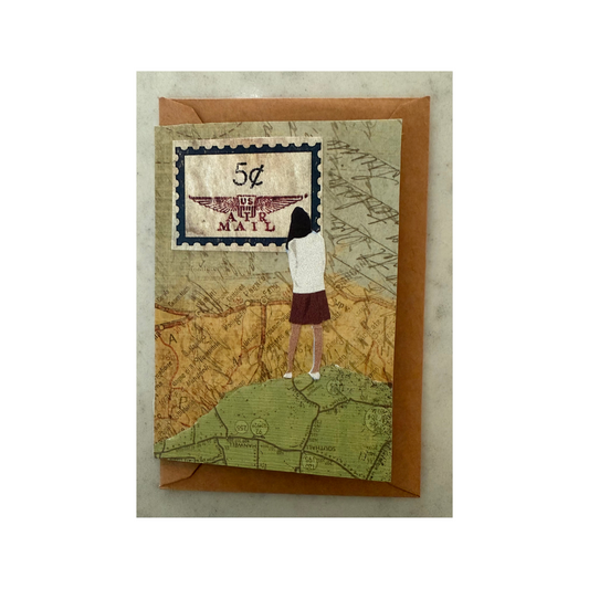 This mini collaged card is made of paper and features a woman in a short maroon skirt and white sweater looking away at a map sky while standing on a map ground, and there is a vintage postage stamp in left top corner.  It also features a brown Kraft envelope for card