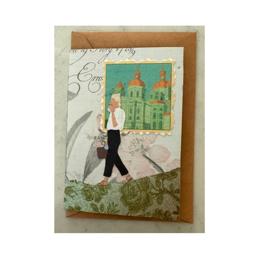 This mini collaged card is made of paper and features a blond-haired woman in black pants, white blouse, and sandals walking while sipping coffee and carrying a purse.  She is walking on a green flowered print hill with a multi-colored sky background behind her, and in the right corner is a cut out of an Italian city scene