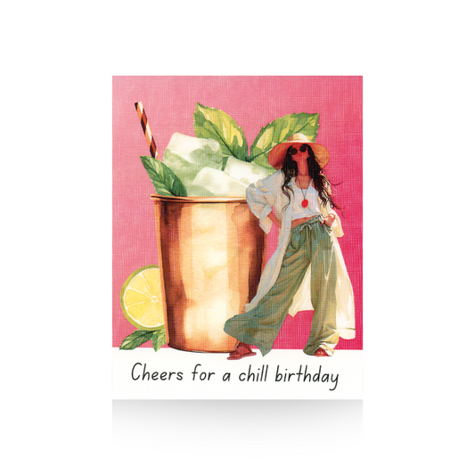 This birthday card features an illustrated Moscow mule cocktail in a copper cup with ice, mint leaves, and a straw on top of the cup.  To the right of the cup is a modern illustrated lady wearing green wide-legged pants, a white cropped top and a long white shirt.  The background of the card is pink and the base is white.  "Cheers for a chill birthday" is written on the base of the card