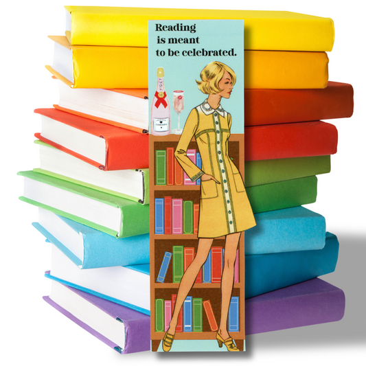 This photo shows a stack of bright-colored books with a bookmark standing in front, featuring a vintage woman in a short yellow dress standing in front of a bookcase. On the top shelf is a pink champagne bottle and pink champagne flute with the message "Reading is meant to be celebrated."
