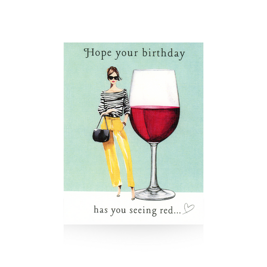 This birthday care features a modern illustrated lady in yellow pants and a black and white striped top.  She is carrying a black purse and has sunglasses on.  To her right is an oversized red wine glass.  The greeting "Hope your birthday has you seeing red" is written at the top and bottom of the card