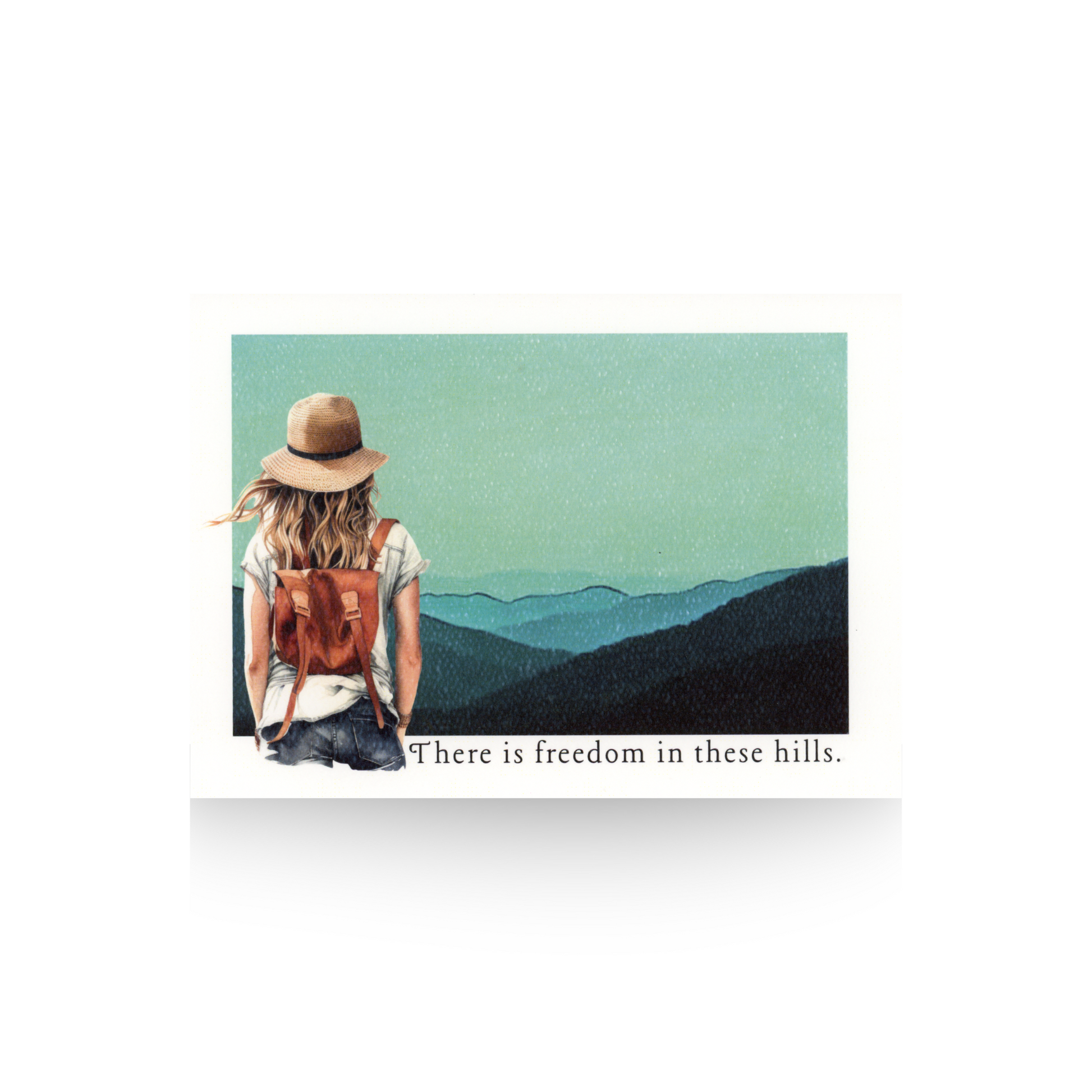 Woman with a backpack and hat with long brown hair and wearing blue jeans and a white t-shirt looking at mountains with text 'There is freedom in these hills'.