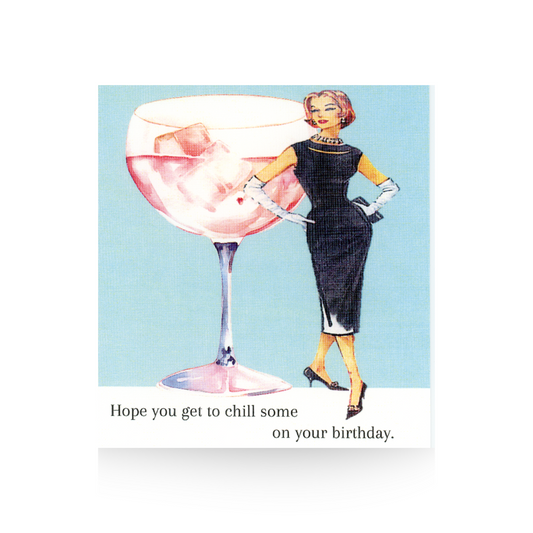 This birthday card features an oversized rose wine spritzer drink in a wine glass.  To the right of the glass is a vintage illustrated lady in a black cocktail dress.  She has her hands on her hips.  The background of the card is light blue and the base is white.  The greeting "Hope you get to chill some on your birthday" is written on the base of the card