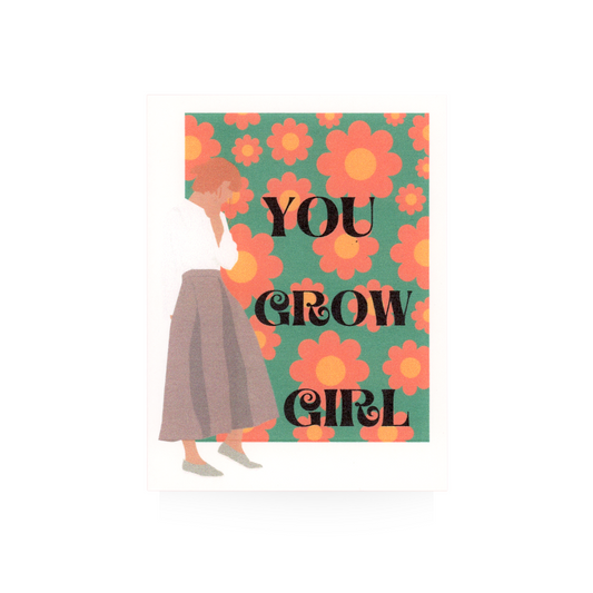 This greeting card features a retro-flowered background of orange, yellow, and green.  "YOU GROW GIRL" is written in large font down the card.  To the left of the message is a modern woman standing in profile and she is wearing a mauve skirt and white long-sleeved blouse